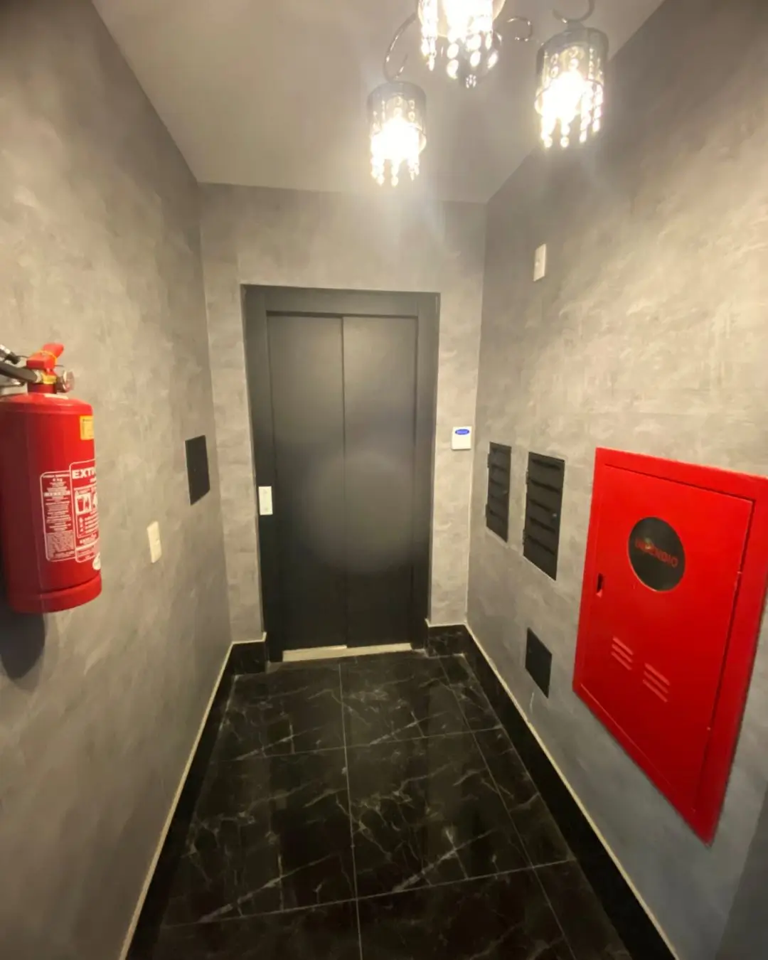 Corredor de prédio residencial com porta preta, Belo Horizonte