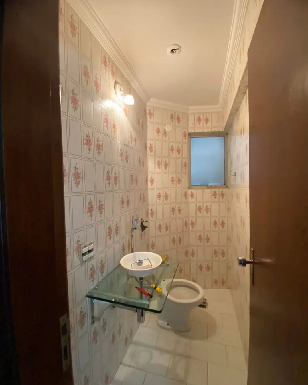 Banheiro com parede em padrão floral e bancada de vidro, Belo Horizonte