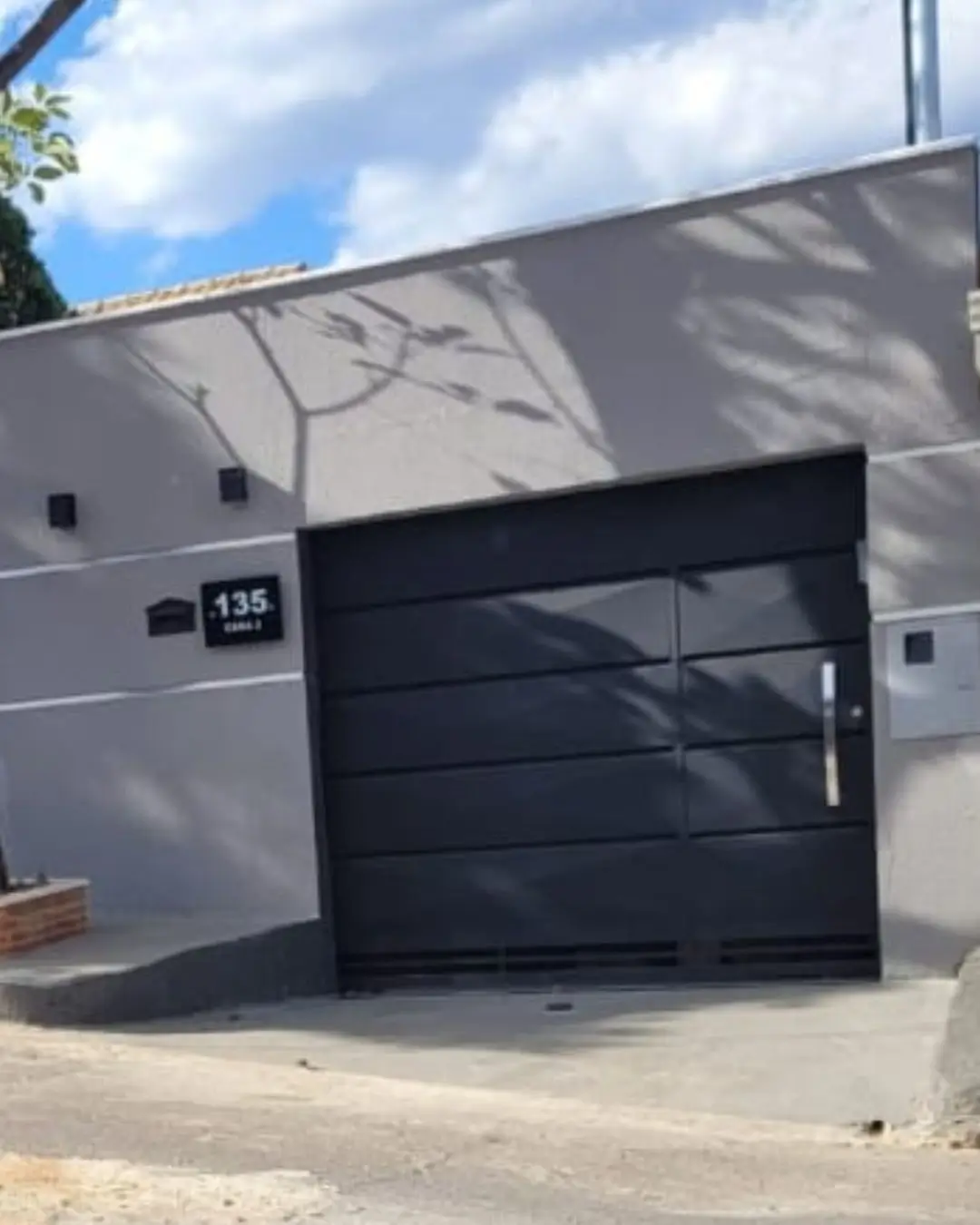 Fachada residencial com portão de garagem preto em Belo Horizonte