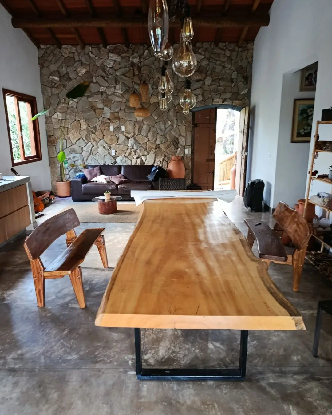 Sala de jantar com parede revestida em pedra e mesa rústica de madeira maciça, projeto em Belo Horizonte